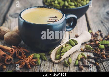 Tasse gesunden ayurvedischen Masala-Tee oder Kaffee mit aromatischen Gewürzen. Zimtstangen, Kardamom, allspices und Anis auf Holztisch. Stockfoto