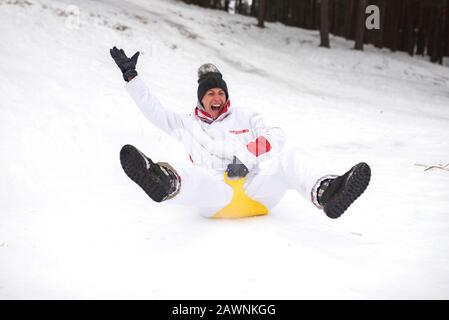 Eine Erwachsene Frau reitet auf Eisschlitten vom Berg. Emotional.Winterspaß. Stockfoto