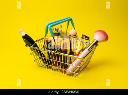 Makeup Produkte Fondant, Mascara, Parfüm, Pinsel, mit Kosmetikbeutel Warenkorb auf Farbhintergrund Stockfoto