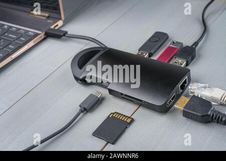 USB Typ-C-Adapter oder Hub in den Laptop mit verschiedenen Accessoires - Pendrives, HDMI, Ethernet, Speicherkarte, Kabel verbunden. Stockfoto