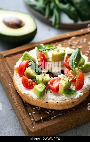 Bagels Toast mit Avocado und Tomaten, garniert mit Hanfsamen. Vegetarischer Imbiss, Frühstück oder Mittagessen Stockfoto