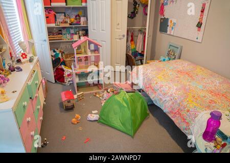 In einem unordentlichen, aber gut genutzten kleinen Mädchen-Schlafzimmer mit Spielzeug und Sachen, die verstreut sind und Schranktüren öffnen sich. Stockfoto