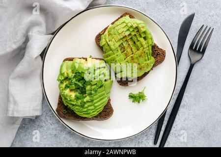 Roggenbrot Toast mit Avocado und Cilantro auf Platte, Draufsicht. Gesundes veganes vegetarisches Essen Stockfoto