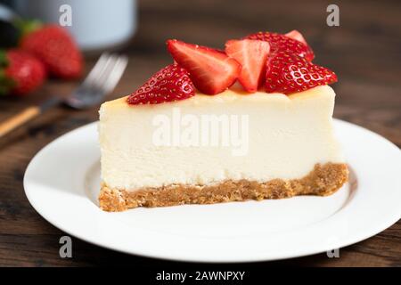 Käsekuchen mit Erdbeeren. Einfarbiger Käsekuchen im klassischen Stil in New York auf weißem Teller mit Nahansicht Stockfoto