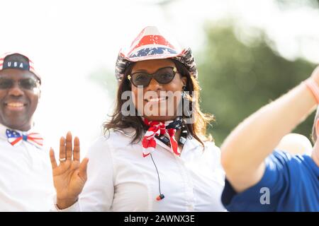Arlington, Texas, USA - 4. Juli 2019: Arlington, 4. Juli Parade, Frau, die einen Cowboyhut mit den Farben der amerikanischen Flagge, Lächeln und Wellen trägt Stockfoto