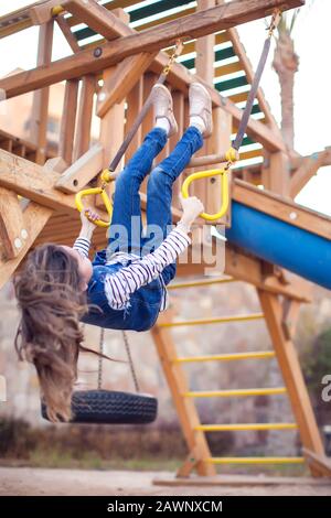 Ein lächelndes kleines Mädchen, das auf dem Spielplatz im Freien klettert. Konzept für Kindheit und Aktivität Stockfoto