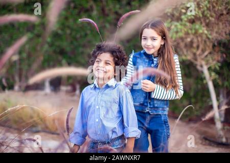 Zwei glückliche Kinder, verschiedene Rennjungen und Mädchen, die im Freien spielen. Konzept für Kindheit und Emotionen. Stockfoto