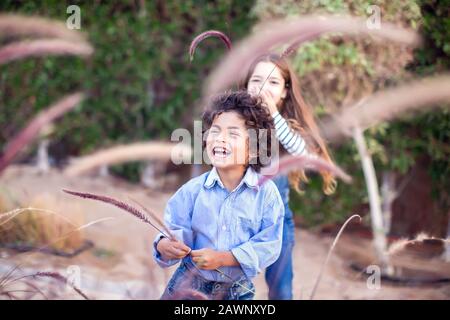 Zwei glückliche Kinder, verschiedene Rennjungen und Mädchen, die im Freien spielen. Konzept für Kindheit und Emotionen. Stockfoto