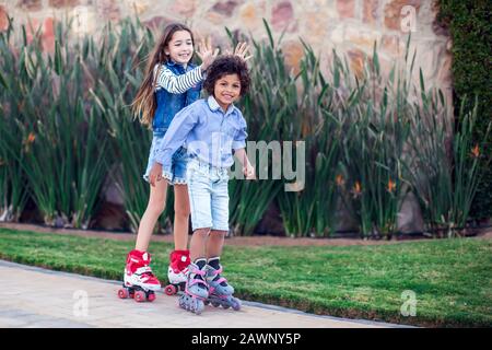 Zwei glückliche Kinder Junge und Mädchen Roller Skaten im Park. Kinder-, Lifestyle- und Aktivitätskonzept Stockfoto