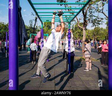 Der ältere Chinese trainiert im Outdoor-Fitnessstudio, das auf Barschienen schwingt, im Tiantan Park, Peking, China, Asien Stockfoto