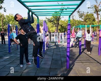 Der ältere Chinese trainiert im Outdoor-Fitnessstudio, das auf Barschienen schwingt, im Tiantan Park, Peking, China, Asien Stockfoto