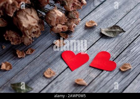 Rote Papierherzen und getrocknete Blumen auf grauem Holzhintergrund Stockfoto