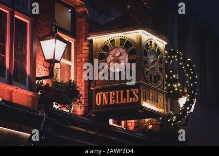 DUBLIN, IRLAND, 24. Dezember 2018: Blick auf die Uhr an der Außenseite des O'Neill's Pub und Küche auf Suffolk Street, schwach beleuchtet und dekoriert Stockfoto