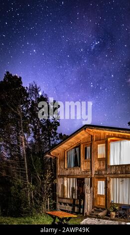 Bariloche, ARGENTINIEN, 19. JUNI 2019: Außenansicht einer gemütlichen und entspannenden Holzhütte im Wald mit einem wundervollen Sternenhimmel Stockfoto