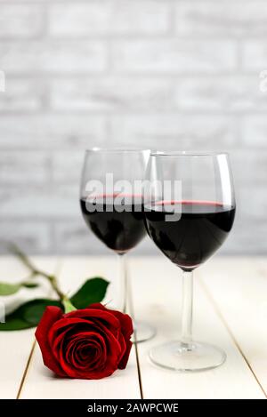 Valentinstag Konzept. Zwei Gläser Wein und Rot stiegen auf einem weißen Holztisch auf. Selektiver Fokus. Stockfoto