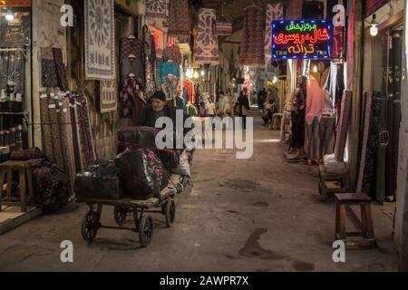 Isfahan, IRAN - 20. AUGUST 2018: Älterer alter Mann, ein Auslieferer, der einen Wagen in den Straßen des Isfahan Covered Basar zieht, ein Wahrzeichen des persischen Bogens Stockfoto