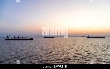 Frachtschiffe bei Sonnenuntergang ankerten vor Buenos Aries und warteten darauf, Fracht zu laden. Stockfoto