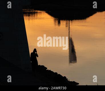 Spiegelung des Gebäudes in einem See mit der Silhouette Einer Person, die ein Foto gemacht hat Stockfoto