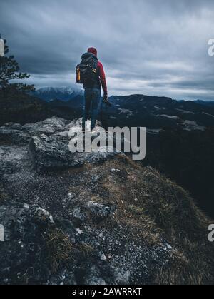 Mann mit Kamera steht an einem wolkigen Moody auf der Bergkuppe Stockfoto