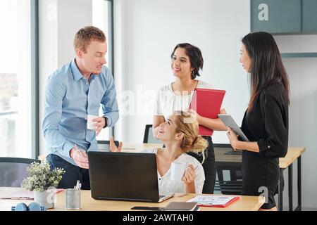Team junger, fröhlicher Führungskräfte, die über ein neues kreatives Projekt diskutieren Stockfoto