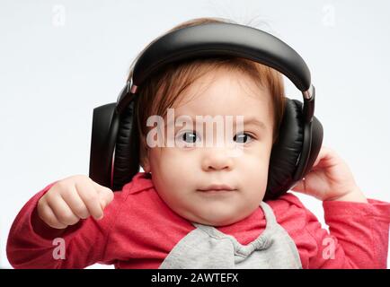 Kleines Mädchen mit Kopfhörern Nahaufnahme Portrait isoliert auf weißem Studiohintergrund Stockfoto