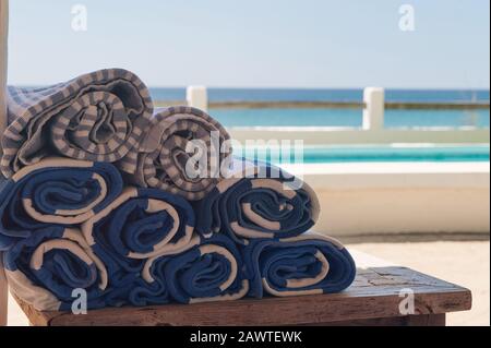 Stapel von Poolhandtüchern auf Holztisch im Strandhintergrund Stockfoto