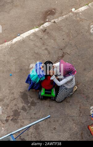 Ein armes obdachloses kambodisches Mädchen und eine verarmte Frau, die als Geiger arbeiten, pflücken Flöhe aus den Haaren eines jungen Mädchens in Kampong Cham, Kambodscha. Stockfoto