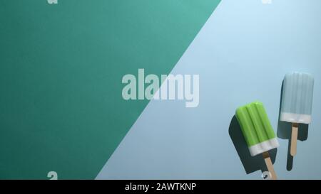 Draufsicht über Limette und blaue Himbeere Aromen Popsicles und Kopierraum, Sommer Minimalkonzept auf flachem, grünem und blauem Hintergrund Stockfoto
