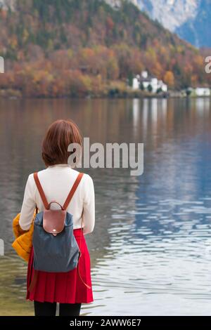 Asiatisches Reisegirl aus der Rückstellung am Hallstatter See Österreich im Herbst; Freiheit ruhiges Entspannungskonzept Stockfoto