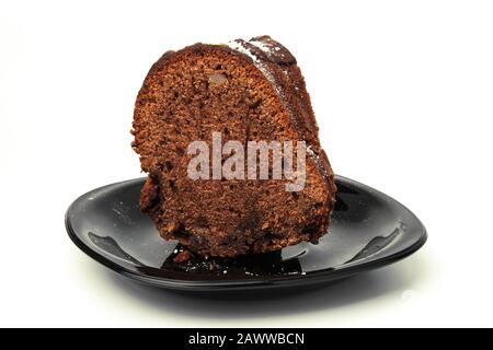 Ein Stück Kuchen auf einer schwarzen Untertasse isoliert auf Weiß Stockfoto
