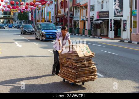 Lokaler Mann schiebt einen Wagen mit gefaltetem Pappe entlang der South Bridge Road, Chinatown, Singapur, Asien Stockfoto