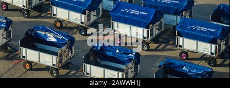 Hannover, 8. Februar 2020: Reihen mit Gepäcktransportern für den Transport von Reisegepäck zum Flugzeug auf dem Asphalt Stockfoto