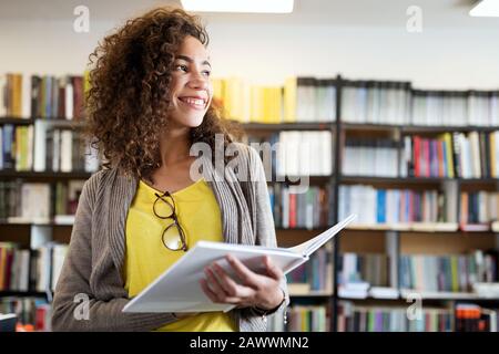 Bildung, Gymnasium, Universität, Lernen und Menschen Konzept. Lächelnde Studentin liest Buch Stockfoto