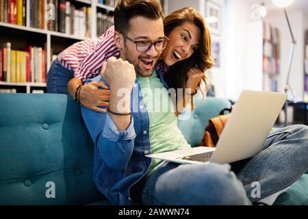 Überraschte glückliche junge Paare mit Blick auf den Laptop Stockfoto