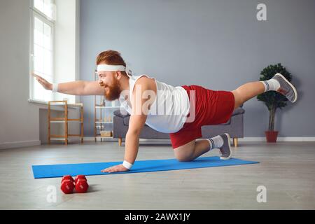 Lustiger fetter Mann, der Yoga-Übungen im Raum macht. Stockfoto