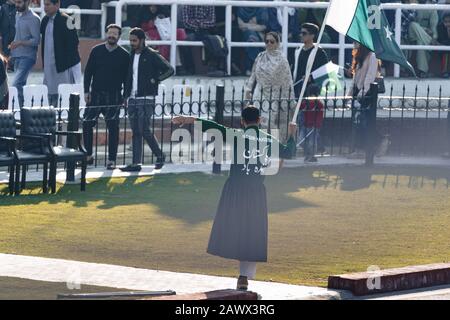 Wagah, Pakistan - Februar 8, 2020: Pakistanischer Performer Mann hält eine Fahne und hypert die Menge vor der Abschlussfeier der Grenze zu Wagah mit Indien Stockfoto