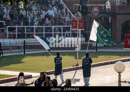 Wagah, Pakistan - Februar 8, 2020: Zwei pakistanische Männer winken Flaggen und überruchen die Menge für die Abschlussfeier der Grenze zu Wagah mit Indien Stockfoto