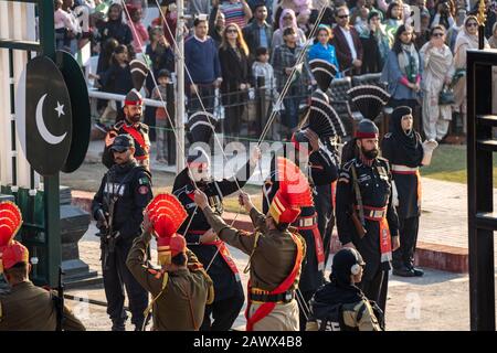 Amritsar Indien - Februar 8, 2020: Indische Grenzschutztruppe und Pakistan Rangers (schwarze Uniformen) untere Flaggen bei der Abschlussfeier der Grenze zu Wagah Stockfoto