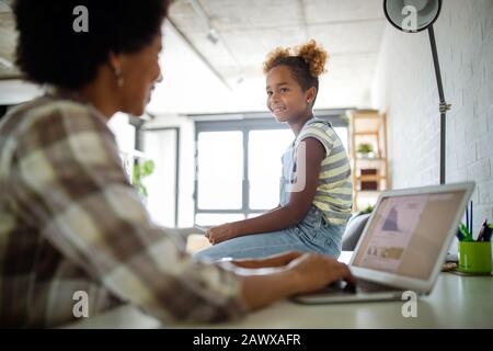 Glückliche Familie, Mutter und Kind Tochter zu Hause arbeiten auf dem Computer Stockfoto