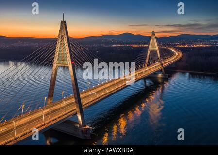 Budapest, Ungarn - Blick Auf die schöne beleuchtete Megyeri-Brücke über die Donau mit blauem und orangefarbenem Himmel bei Sonnenuntergang Stockfoto