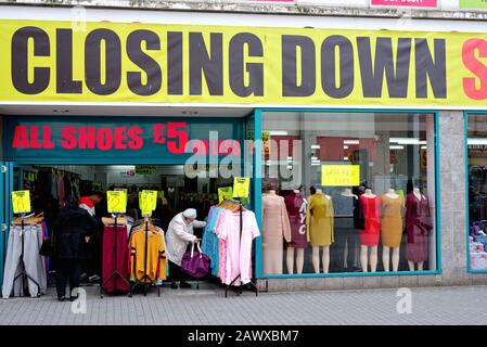 Vor einem billigen Bekleidungsgeschäft mit einem großen Abschließungsschild über dem Eingang in der Hounslow High Street, West London England UK Stockfoto