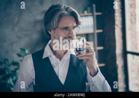 Portrait des atemberaubenden alten Mannes Großvater Rentner erfolgreicher Firmeninhaber Hauptvermarkter Getränk Glas Whisky tragen formalwear Weste in Stockfoto