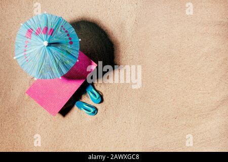 Spielzeug Sonnenliege mit Sonnenschirm und Strandsandalen oder Dongs an einem sandigen Strand, Kopierraum, Draufsicht. Stockfoto