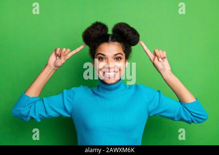 Foto der lustigen hübschen dunklen Hautdame, die Finger auf neuen Friseursalon zeigt, coole schöne Brötchen, die den Friseursalon Stylisten raten, blauen Turnleneck-Pullover isoliert zu tragen Stockfoto