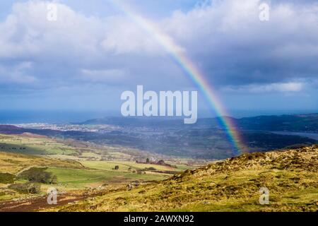 Regenbogen auf Tal y Fan Berg bei wechselhaftem Wetter vor Sturm Ciara in Snowdonia mit Blick auf Llandudno an der Küste. Conwy Nordwales Großbritannien Stockfoto