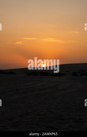 Blick auf den schönen Sonnenuntergang bei Desert Safari Camel Ride, einem Wahrzeichen für Wüstenaktivitäten, in Al Wakrah, Katar. Stockfoto