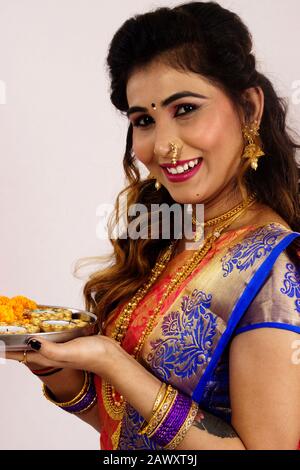 Indisches Modell mit traditioneller Maharashtrian-Seidengaree, mit Puja-Tablett, lächelnd und Blick auf die Kamera, Nahaufnahme Stockfoto