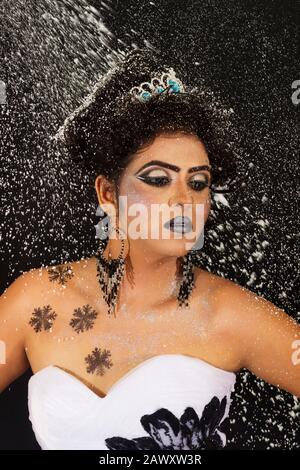 Modestudio Porträt der schönen Frau in schwarz-weißem Gown mit afro Locken Frisur. Mit einem Tiara mit silberfarbenem Konfettihintergrund Stockfoto