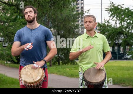 Krasnojarsk, Russland, 30. Juni 2019: Zwei europäische Männer spielen im Sommer afrikanisches Schlagzeug in einem öffentlichen Park. Stockfoto