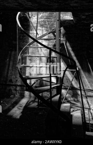 Rostige Wendeltreppe aus Metall in einer verlassenen alten Fabrik Stockfoto